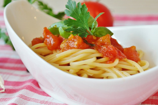 Spaghetti mit Tomatensauce und frischen Kräutern in einer weißen Schale angerichtet